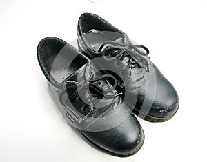 Old black safety shoes that have been used a lot and are dirty for a long time. White background isolated