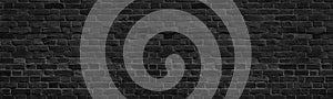 Old black shabby brick wall wide panoramic texture. Dark grey rough masonry. Aged brickwork panorama. Abstract grunge background