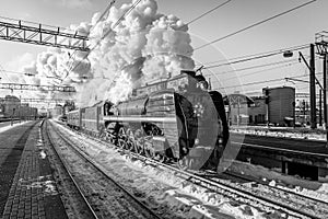 Old black steam locomotive in Russia in the winter on the background of the Moscow railway station