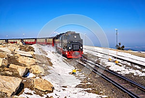 Old black steam locomotive on the top of a snowy mountain with a clear blue sky in the background