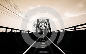 old black steel train bridge Lampang Thailand to Chiangmai Thailand in the evening with blue sky cloud and sun, Black White