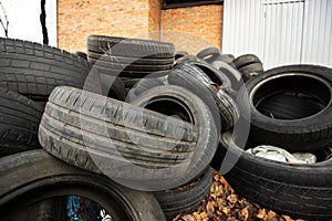 old black used car tires heaped with leaves