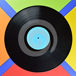 Old black vinyl record on multicolored square