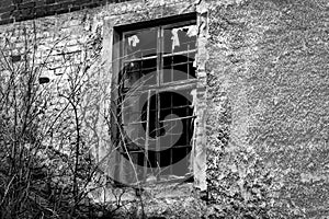 Old black and white damaged wall with a barred window