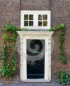 Old black wooden door with white frame on brown brick wall.