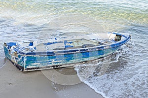 Old blue abandoned fishing boat on the sand beach