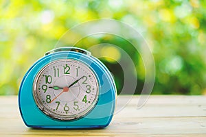 Old blue alarm clock on wooden table