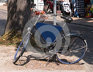 Old blue bicycle leaning against pole with blank blue sign