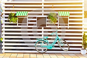 Old blue bicycle near a store or bakery wall with wooden white boards in a rustic style with chalkboard, signboards with sunshades