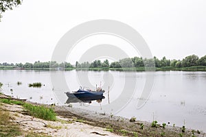 Old blue boat on the river bank. picturesque water landscape. calm and relaxing summer day