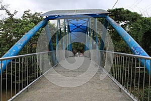 Old Blue bridge leading to an area with many trees