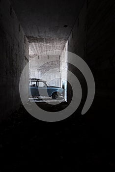 An old blue car in an abandoned concrete catacomb photo