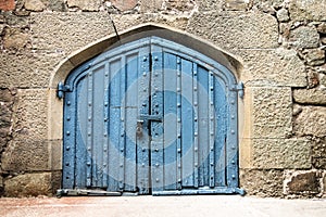 Old blue door or gate in stone wall, locked