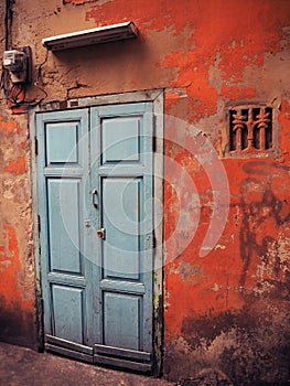 Old blue door on a red wall.