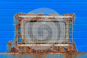 Old blue door with rusty window with metal grilles