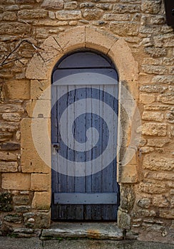 Old blue door in yellow stone wall with padlock