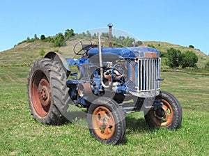 Old blue farm tractor in field.