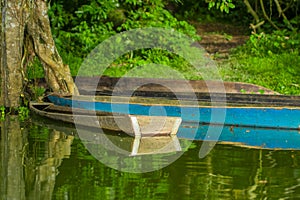 Old blue fishing wooden boat in a calm lake water