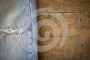 Old blue jeans with torn texture on wood