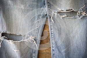 Old blue jeans with torn texture on wood