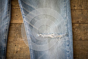 Old blue jeans with torn on wood background