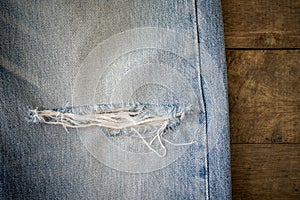 Old blue jeans with torn on wood background