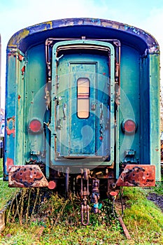 Old blue passenger carriage with front door on disused train tracks at old station