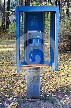 Old blue payphone in a booth on the street