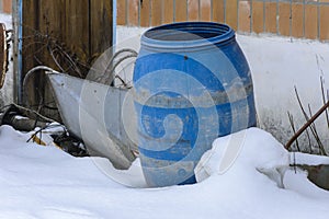 The old blue plastic barrel is thrown into the snow