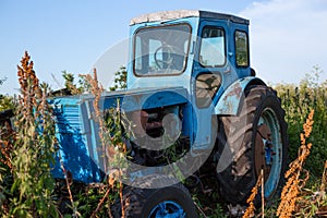 Old blue rusted tractor on the grass.