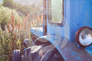 Old blue rusted tractor on the grass.