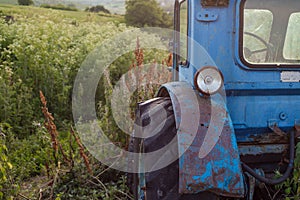 Old blue rusted tractor on the grass.