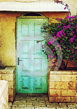 Old blue rustic wooden door and flowers. filtered image with texture overlay