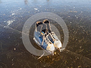 Old blue skates on the ice of the lake on an early sunny morning