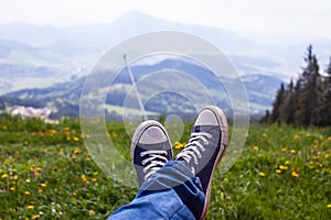 Staré modré tenisky na nohách mladého chalana s krásnym výhľadom na hory v pozadí