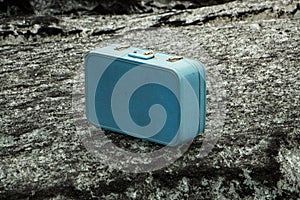 Old blue suitcase on a rock