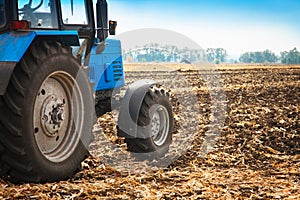 Old blue tractor in a empty field. Agricultural machinery, field work.