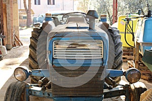 Old blue tractor parked in shed of farm.