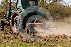 An old blue tractor plows a field and cultivates the soil. Agriculture