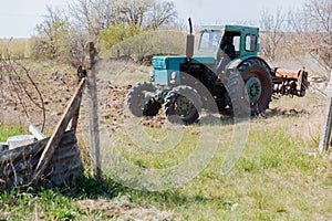 An old blue tractor plows a field and cultivates the soil. Agriculture