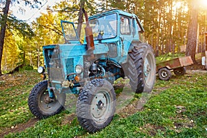 An old blue tractor stands in a farmyard