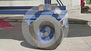 Old blue trailer wheel loaded with a yacht moves along a concrete surface