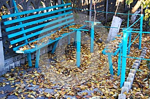 Old blue wooden bench and fallen autumn leaves