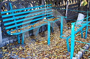 Old blue wooden bench and fallen autumn leaves