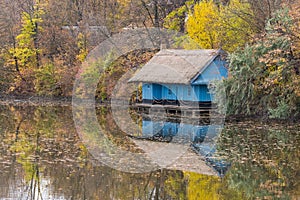Old Blue Wooden House Reflected on the Lake and Surrounded by Warm Coloured Trees