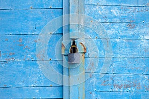 Old blue wooden plank gate with a padlock