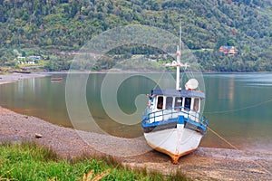 Old boat anchored on the beach of the fjord of Puyuhuapi, Patagonia, Chile photo