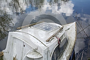 Old boat on the calm water with reflexion of blue sky