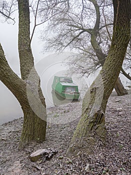 An old boat in the fog covered with frost in a willow grove.