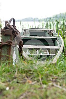 old boat near the shore on a chain with blur forest background